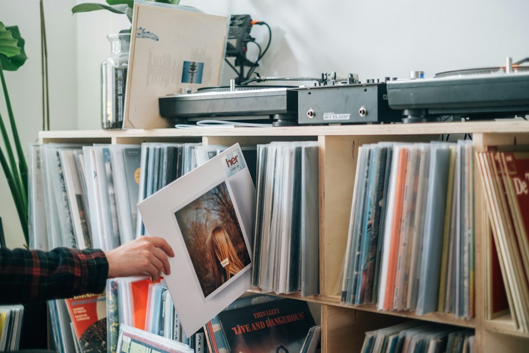 Persona revisa una portada de vinilo frente a una colección de discos